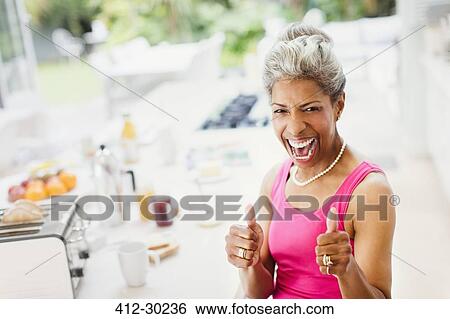 Portrait enthusiastic confident mature women gesturing thumbs-up in kitchen View Large Photo Image Stock Photograph - Portrait enthusiastic confident mature women gesturing thumbs-up in kitchen. Fotosearch