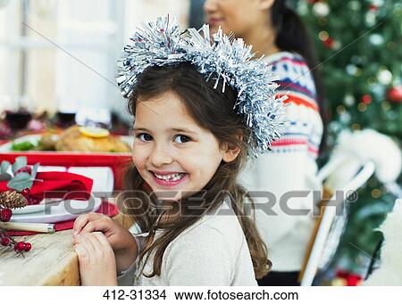 Picture - Portrait enthusiastic girl wearing wreath at Christmas dinner. Fotosearch