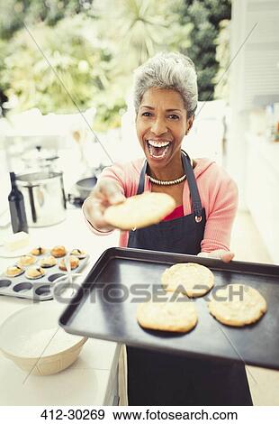 Stock Photo - Portrait enthusiastic mature woman baking cookies in kitchen. Fotosearch