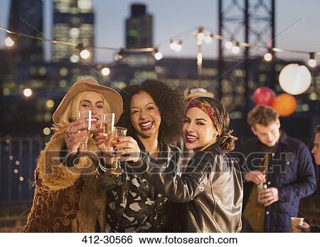 Portrait enthusiastic young adult friends toasting champagne flutes at nighttime rooftop party View Large Photo Image Stock Photograph - Portrait enthusiastic young adult friends toasting champagne flutes at nighttime rooftop party. Fotosearch