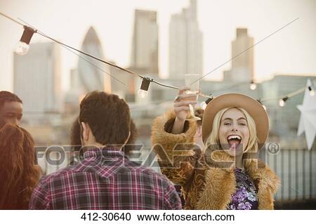 Stock Image - Portrait enthusiastic young woman drinking champagne at rooftop party. Fotosearch