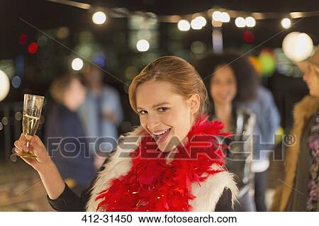 Stock Image - Portrait enthusiastic young woman drinking champagne at rooftop party. Fotosearch