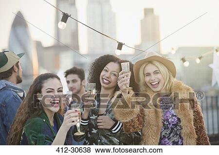 Portrait enthusiastic young women drinking champagne at rooftop party View Large Photo Image Stock Photo - Portrait enthusiastic young women drinking champagne at rooftop party. Fotosearch