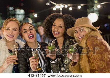 Stock Photo - Portrait enthusiastic young women drinking cocktails at party. Fotosearch