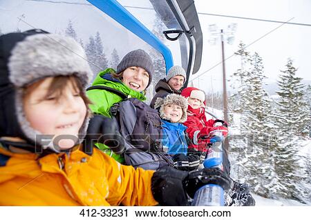 Stock Image - Portrait family riding ski lift. Fotosearch