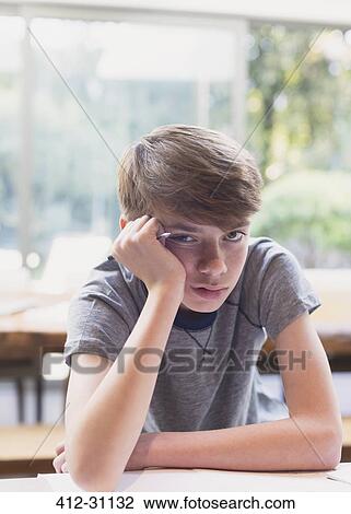 Stock Image - Portrait of bored boy doing homework. Fotosearch