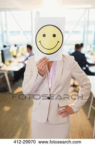 Portrait of businesswoman holding smiley face printout over her face in office View Large Photo Image Stock Image - Portrait of businesswoman holding smiley face printout over her face in office. Fotosearch