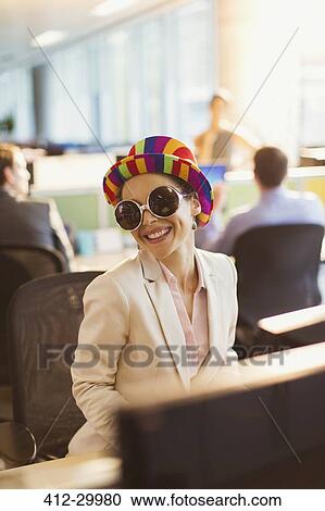 Portrait of smiling businesswoman in silly sunglasses and striped hat working in office View Large Photo Image Stock Image - Portrait of smiling businesswoman in silly sunglasses and striped hat working in office. Fotosearch