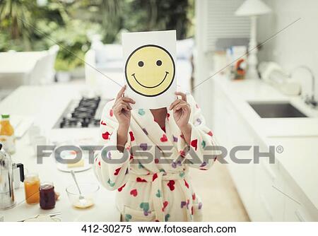 Portrait of women holding smiley face printout over face in kitchen View Large Photo Image Stock Photography - Portrait of women holding smiley face printout over face in kitchen. Fotosearch
