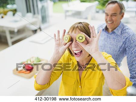 Portrait playful mature woman covering eyes with kiwi slices View Large Photo Image Stock Photo - Portrait playful mature woman covering eyes with kiwi slices. Fotosearch