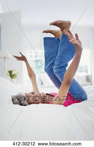 Portrait playful mature woman falling onto bed View Large Photo Image Stock Image - Portrait playful mature woman falling onto bed. Fotosearch