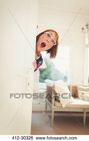 Portrait playful mature woman peering behind door View Large Photo Image Stock Photograph - Portrait playful mature woman peering behind door. Fotosearch