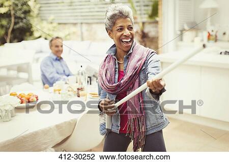 Portrait playful mature woman playing air guitar with stick in kitchen View Large Photo Image Stock Image - Portrait playful mature woman playing air guitar with stick in kitchen. Fotosearch