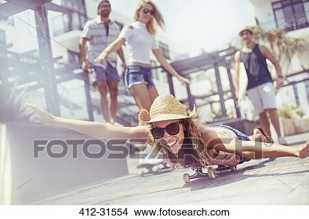 Portrait playful young woman laying riding skateboard on sunny boardwalk View Large Photo Image Picture - Portrait playful young woman laying riding skateboard on sunny boardwalk. Fotosearch