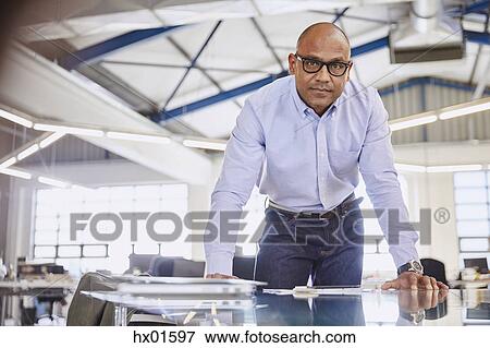 Stock Photo - Portrait serious businessman leaning on conference room table. Fotosearch