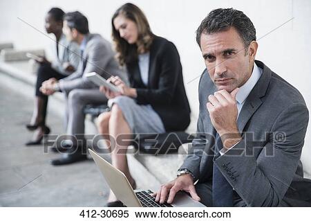 Stock Photography - Portrait serious corporate businessman using laptop. Fotosearch