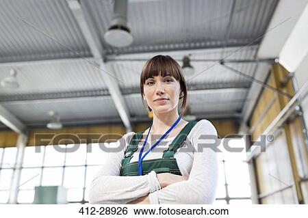 Stock Photograph - Portrait serious female worker with arms crossed in factory. Fotosearch