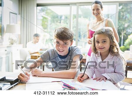 Stock Image - Portrait smiling brother and sister doing homework. Fotosearch