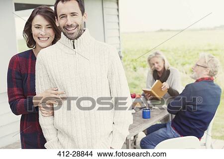 Picture - Portrait smiling brunette couple in sweaters on patio. Fotosearch