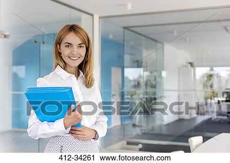 Portrait smiling businesswoman holding folders in conference room View Large Photo Image Stock Image - Portrait smiling businesswoman holding folders in conference room. Fotosearch