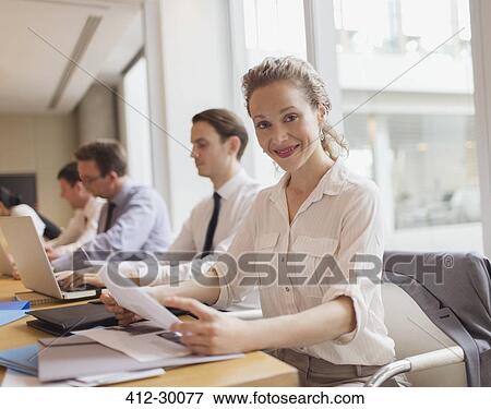 Stock Photo - Portrait smiling businesswoman reviewing paperwork in conference room meeting. Fotosearch