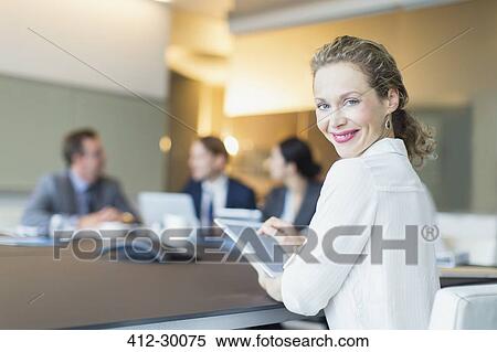 Stock Photography - Portrait smiling businesswoman using digital tablet in conference room meeting. Fotosearch