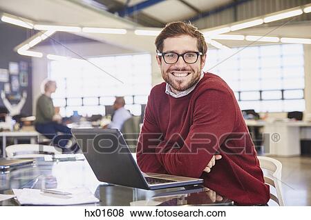Stock Photo - Portrait smiling businesswoman working at laptop in office. Fotosearch