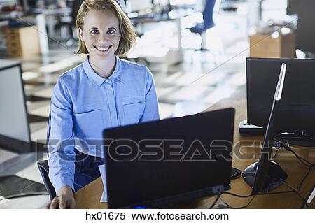 Stock Photography - Portrait smiling businesswoman working at laptop in office. Fotosearch