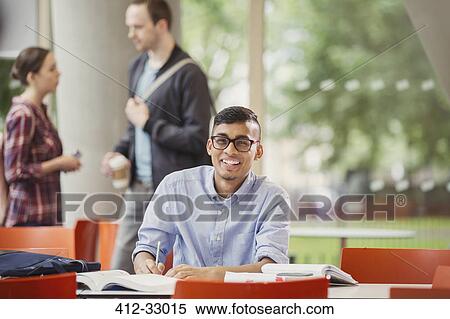 Stock Photography - Portrait smiling college student studying at table. Fotosearch
