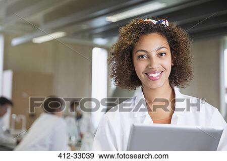 Stock Photo - Portrait smiling college student with digital tablet in science laboratory classroom. Fotosearch