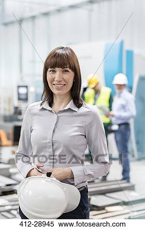 Stock Photography - Portrait smiling engineer with hard-hat in factory. Fotosearch