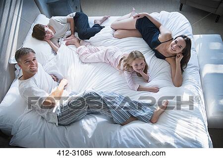 Portrait smiling family in pajamas relaxing on bed View Large Photo Image Stock Photography - Portrait smiling family in pajamas relaxing on bed. Fotosearch