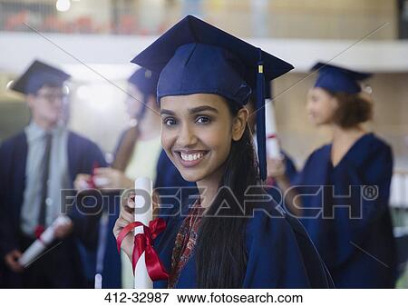 Portrait smiling female college student in cap and gown with diploma View Large Photo Image Stock Photo - Portrait smiling female college student in cap and gown with diploma. Fotosearch