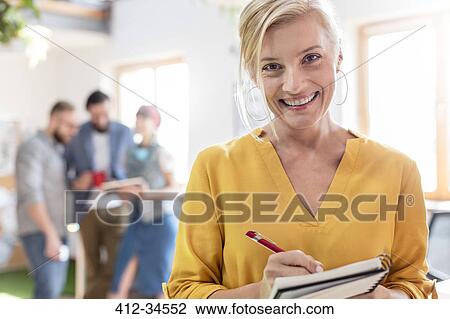 Portrait smiling female design professional taking notes in notebook in office View Large Photo Image Stock Image - Portrait smiling female design professional taking notes in notebook in office. Fotosearch