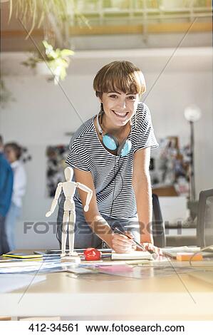 Stock Image - Portrait smiling female design professional with artists figure sketching in office. Fotosearch