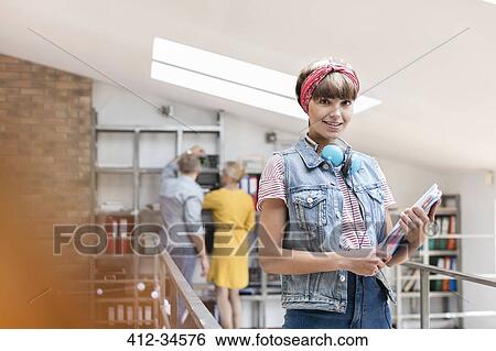 Stock Photograph - Portrait smiling female design professional with headphones in office. Fotosearch