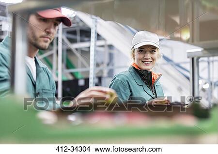 Picture - Portrait smiling female worker inspecting apples in food processing plant. Fotosearch
