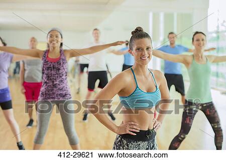 Stock Image - Portrait smiling fitness instructor leading aerobics class. Fotosearch