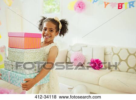 Stock Photo - Portrait smiling girl carrying stack of birthday gifts. Fotosearch