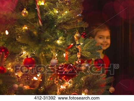 Portrait smiling girl hiding behind Christmas tree View Large Photo Image Stock Image - Portrait smiling girl hiding behind Christmas tree. Fotosearch