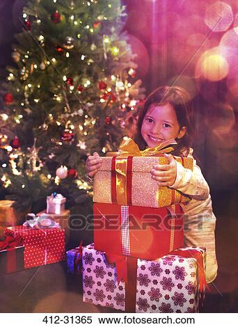 Stock Photography - Portrait smiling girl with stack of Christmas gifts. Fotosearch