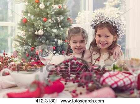 Stock Image - Portrait smiling girls at Christmas table. Fotosearch