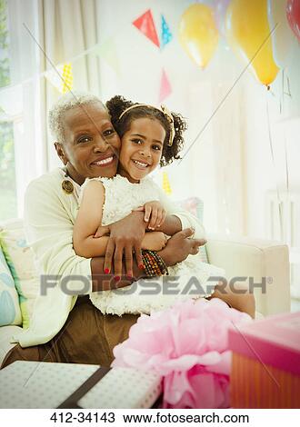 Portrait smiling grandmother and granddaughter hugging at birthday party View Large Photo Image Stock Image - Portrait smiling grandmother and granddaughter hugging at birthday party. Fotosearch
