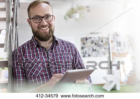 Portrait smiling male design professional using digital tablet in office View Large Photo Image Stock Photo - Portrait smiling male design professional using digital tablet in office. Fotosearch
