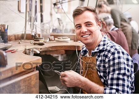 Portrait smiling male jeweler working listening to music with headphones in workshop View Large Photo Image Stock Photography - Portrait smiling male jeweler working listening to music with headphones in workshop. Fotosearch
