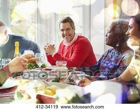 Stock Photo - Portrait smiling man enjoying Christmas dinner at table. Fotosearch
