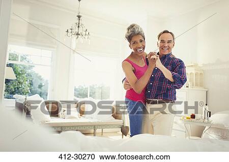 Stock Image - Portrait smiling mature couple dancing in bedroom. Fotosearch