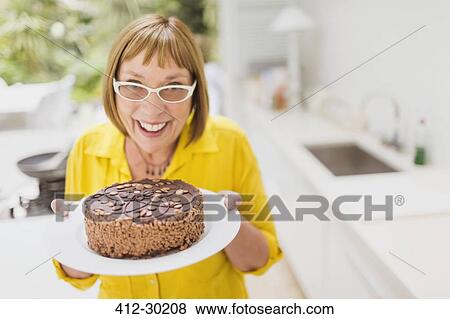Portrait smiling mature woman holding chocolate cake View Large Photo Image Stock Photo - Portrait smiling mature woman holding chocolate cake. Fotosearch