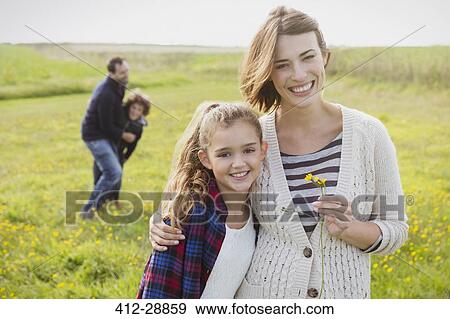 Stock Photo - Portrait smiling mother and daughter in meadow with wildflowers. Fotosearch
