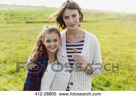 Stock Photography - Portrait smiling mother and daughter in meadow with wildflowers. Fotosearch